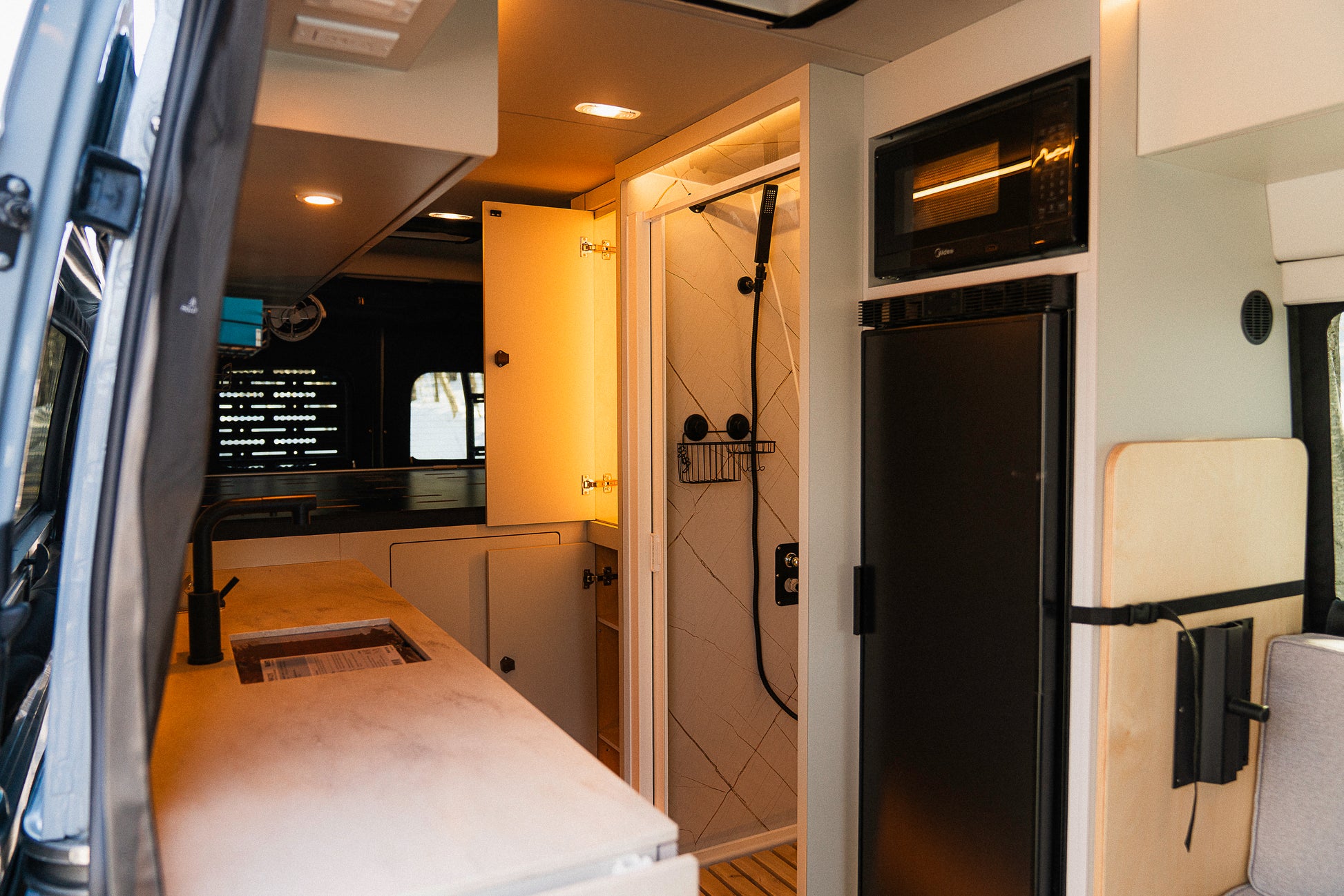Intérieur van New West vue depuis porte latérale avec cuisine, douche, micro-ondes et réfrigérateur