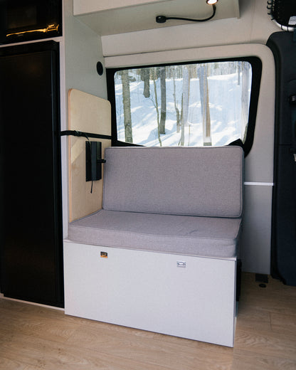 Banc convertible avec coussin et dossier en espace garage van New West, vue vers fenêtre sur forêt enneigée