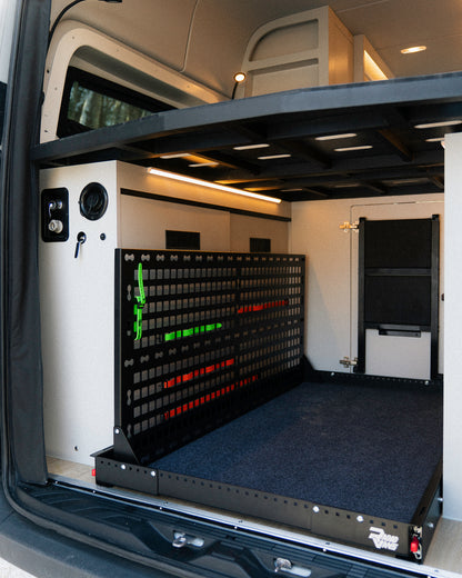 Espace garage van New West avec lit fixe surélevé et panneau de rangement organisateur pour vélos et équipement